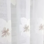 Firana zdobiona beżowymi kwiatami z haftu