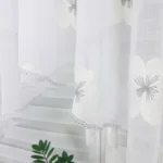 Firana zdobiona szarymi kwiatami z haftu